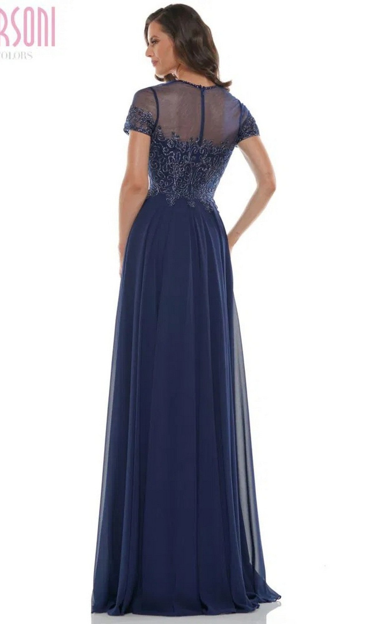 A woman is shown from the back wearing the Marsoni M271 long formal dress in navy, featuring a sheer embroidered bodice, short sleeves, and a floor-length chiffon pleated A-line skirt.